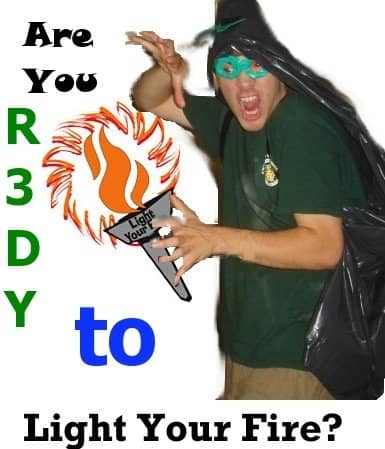 A 2007 photo: a man in a garbage-bag cape and a paper mask brandishes a cardboard torch under the words Are You R3DY to Light Your Fire?